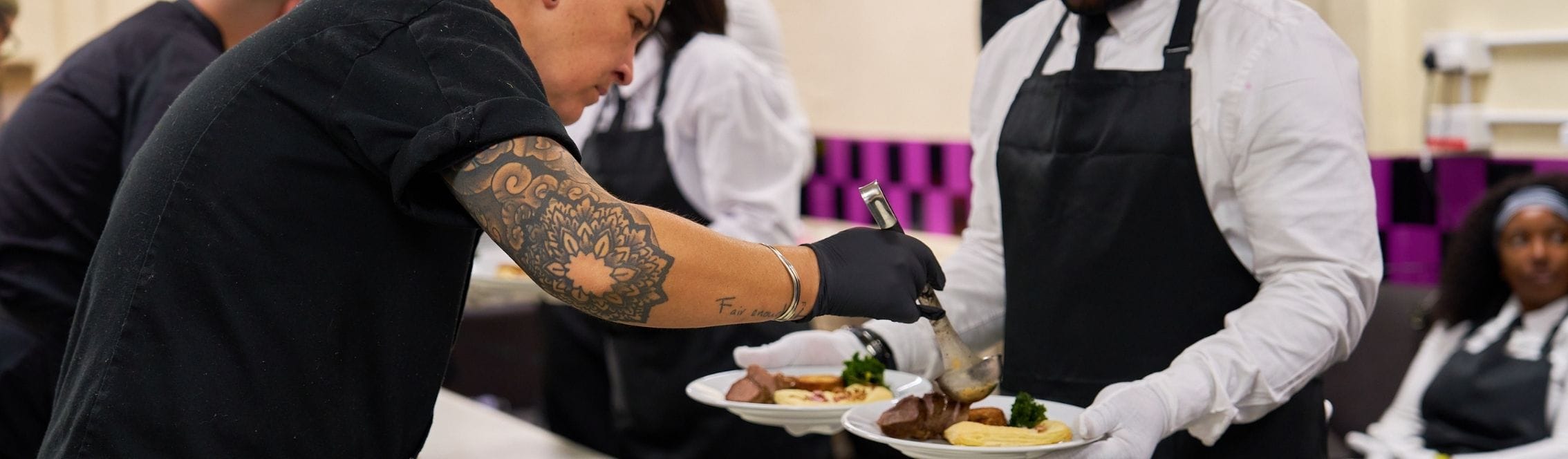 Chef adding final touches to a plated dish before serving guests at a catered event in London